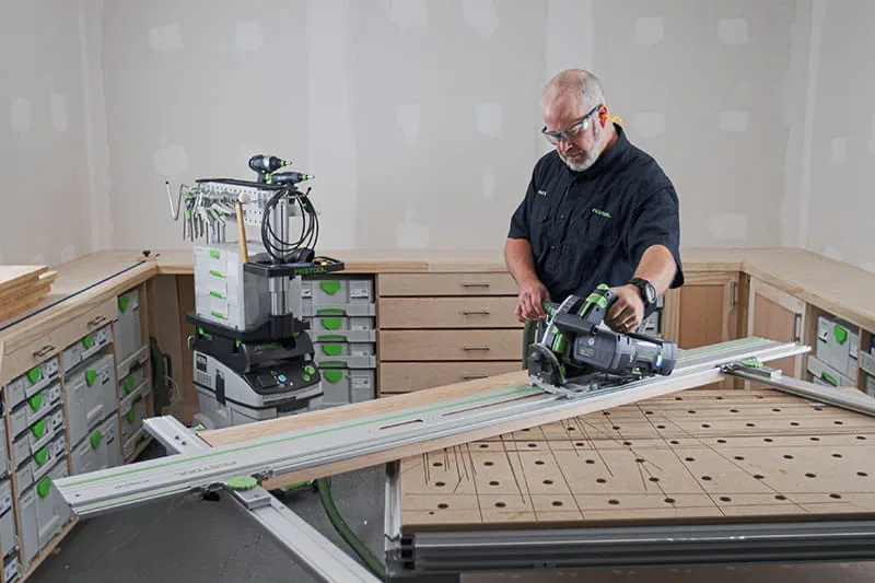 Brent using a track saw on a guide rail cutting wood