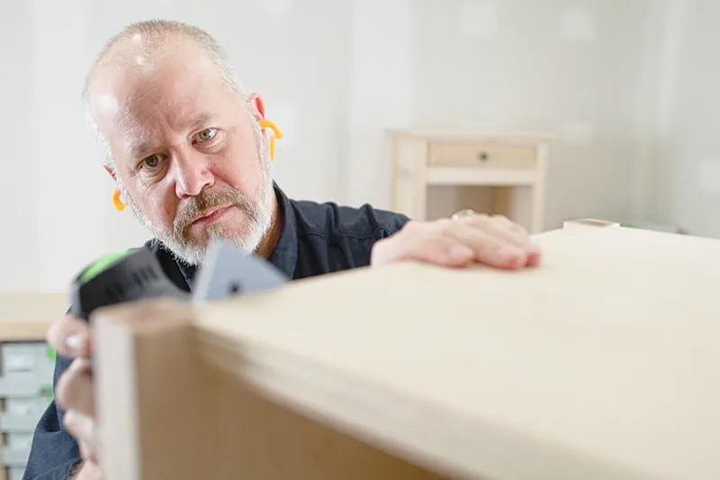 Closeup of Brent sanding sides of table