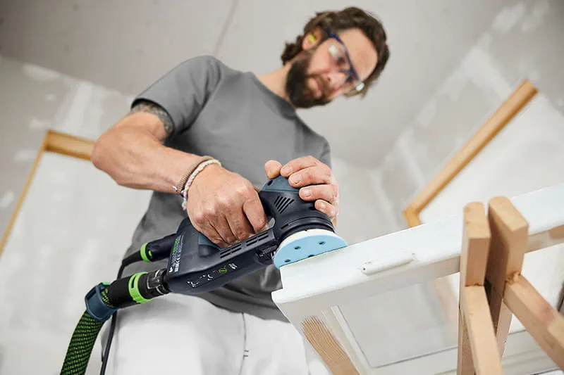 Tradesperson sanding window box with RO 90